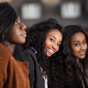 Three women smiling for the camera in a row.