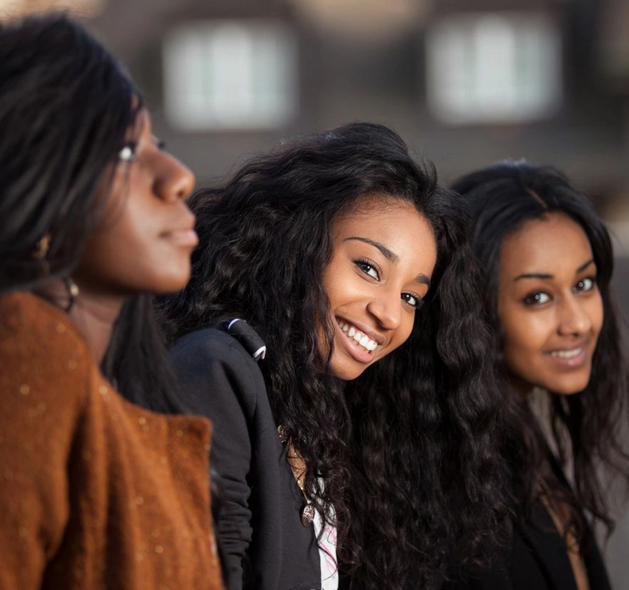 Three women smiling for the camera in a row.