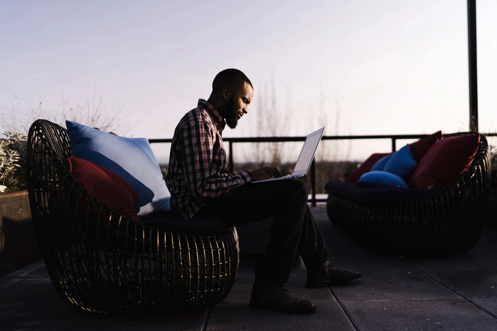 A man sitting on top of a chair using a laptop.