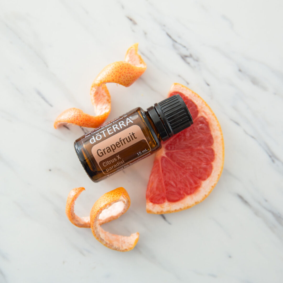 A bottle of essential oil sitting on top of an orange.