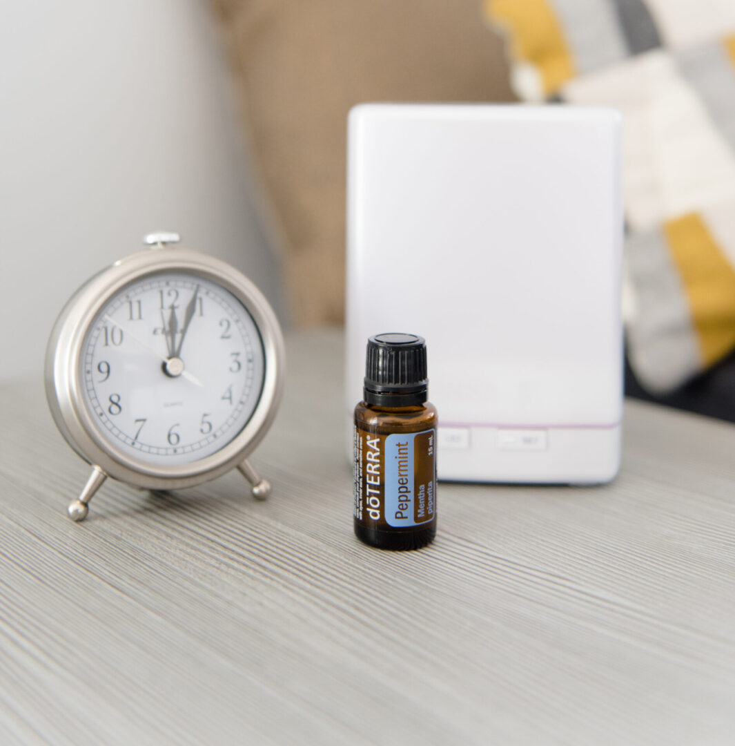 A clock and an essential oil bottle on a table.