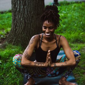A woman sitting in the grass with her hands folded.