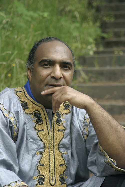 A man in blue and yellow shirt sitting on steps.