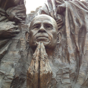 A statue of a man with his hands folded in front of him.