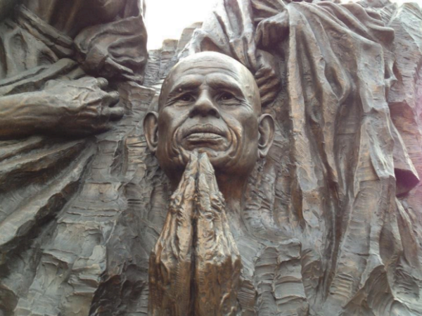 A statue of a man with his hands folded in front of him.